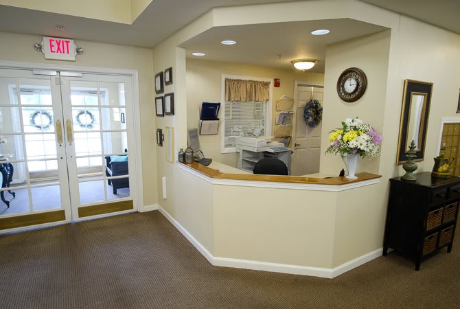 A well-lit reception area featuring a desk adorned with a vase of flowers.