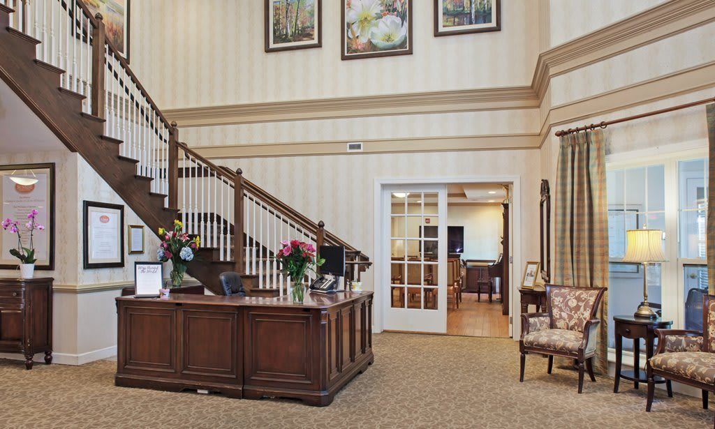 A welcoming reception area with a wooden desk, staircase, and floral decorations.