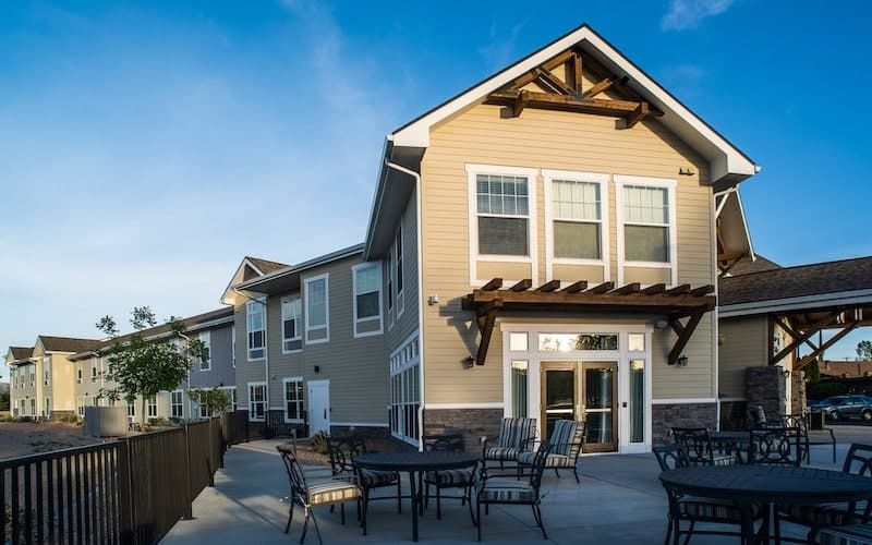 A modern residential building with a spacious patio area and outdoor seating.