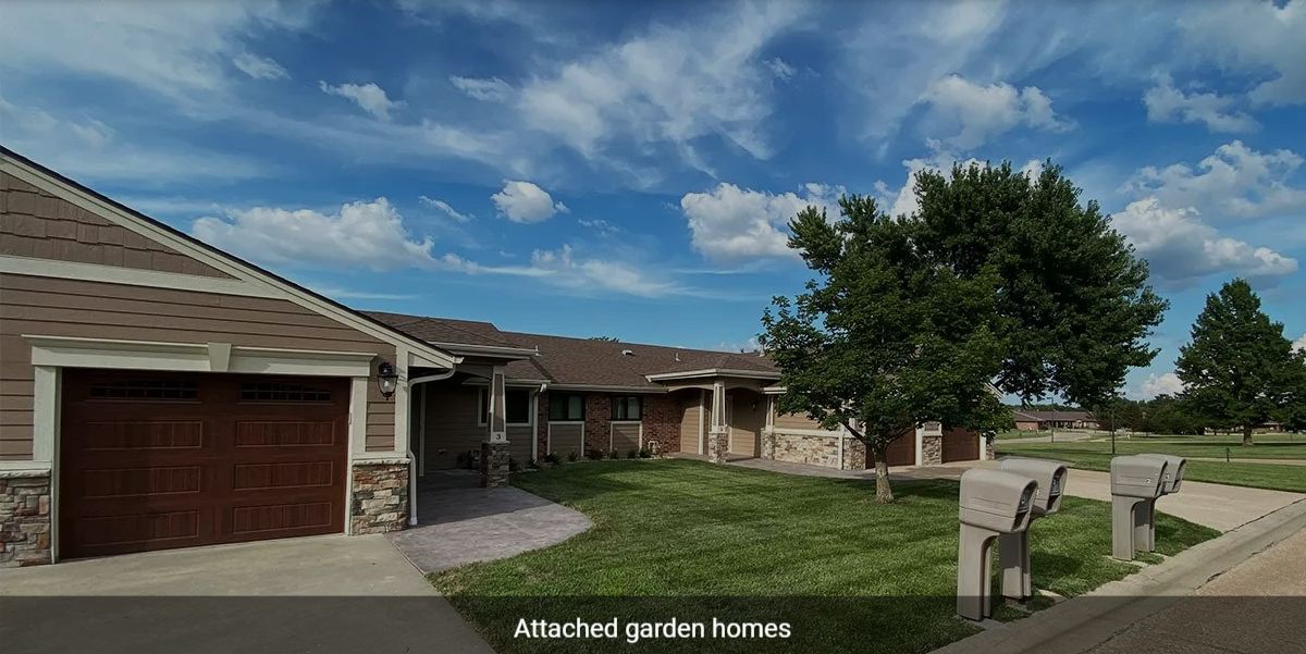 A peaceful suburban neighborhood with attached garden homes under a partly cloudy sky.