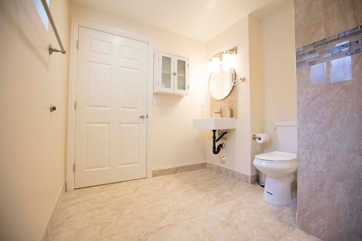 A clean and spacious bathroom with a toilet, sink, and mirror.