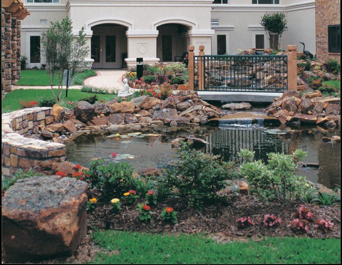 A beautifully landscaped garden with a pond and rocks in front of a building.