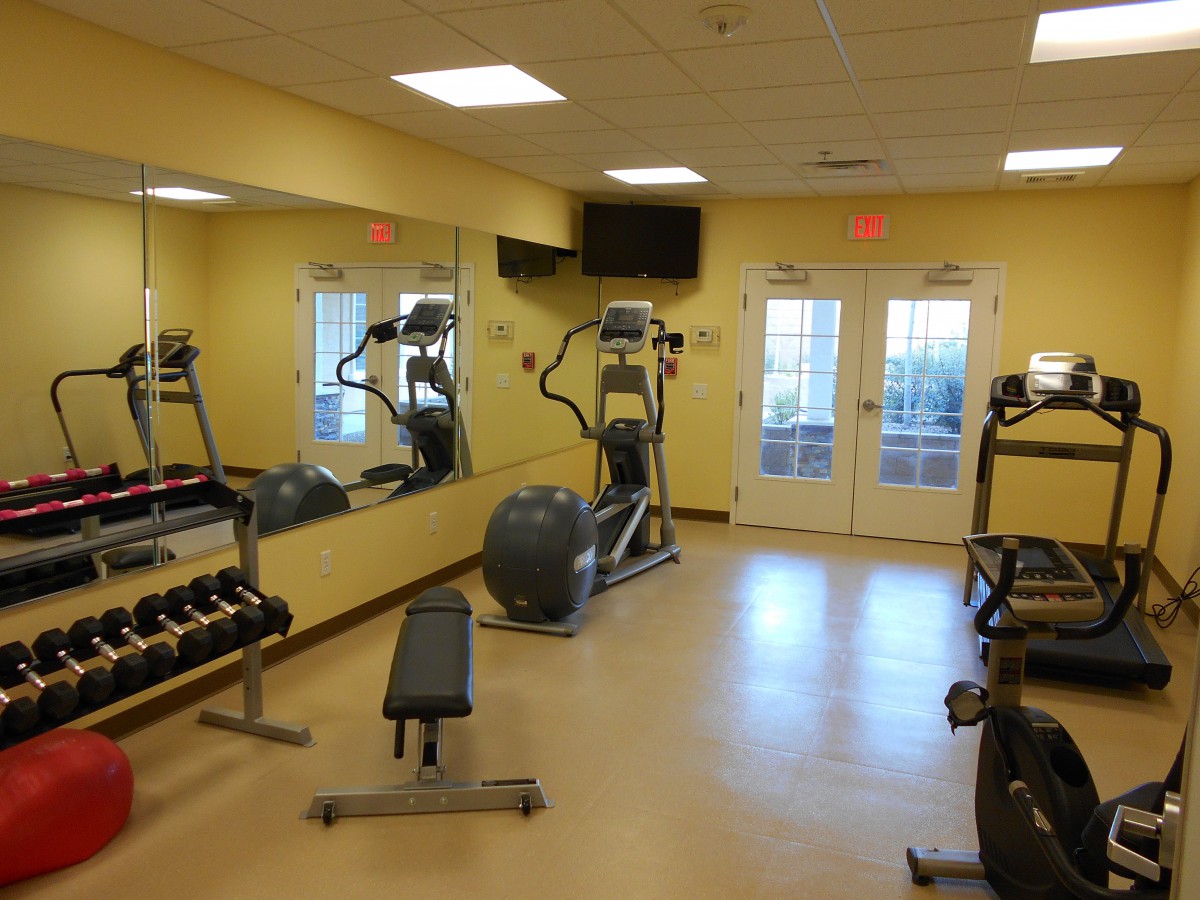 A small indoor gym equipped with exercise machines, weights, and mirrors.