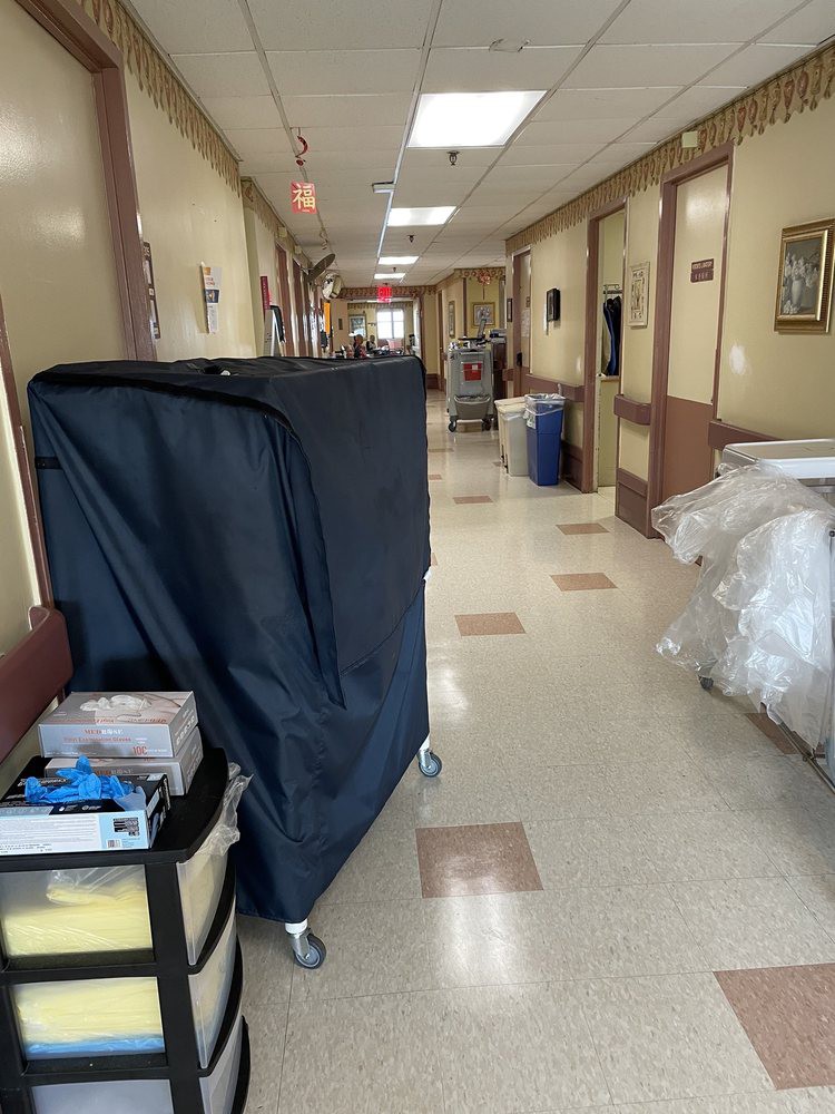 A hospital corridor with medical equipment and cleaning supplies.