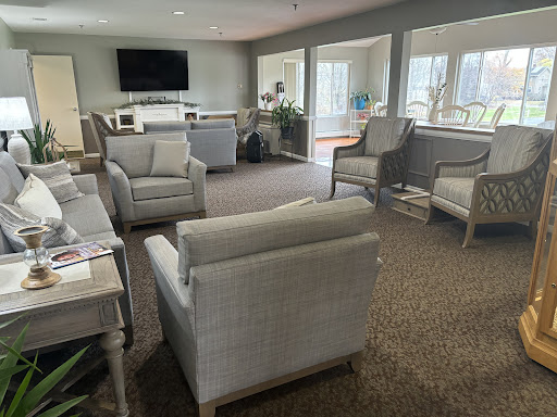 A cozy living room with comfortable seating and a television, bathed in natural light.