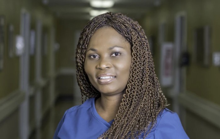 A woman with braided hair wearing professional attire in a hallway.