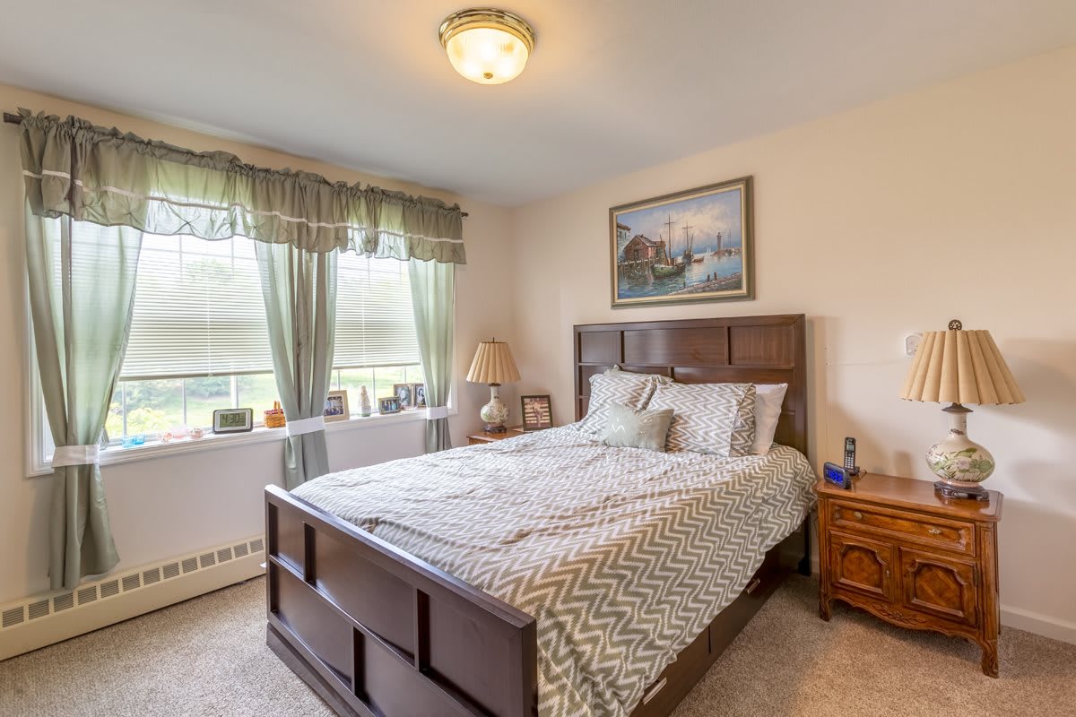A cozy bedroom with a neatly made bed, decorative elements, and natural light streaming through the window.