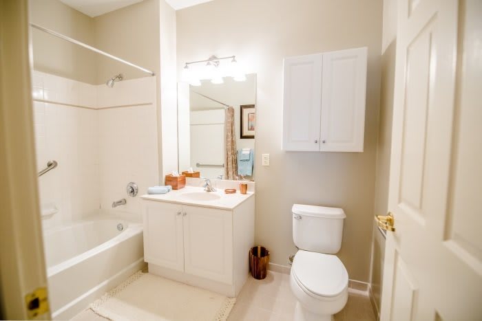 A clean and well-lit bathroom featuring a bathtub, toilet, sink, and storage cabinet.