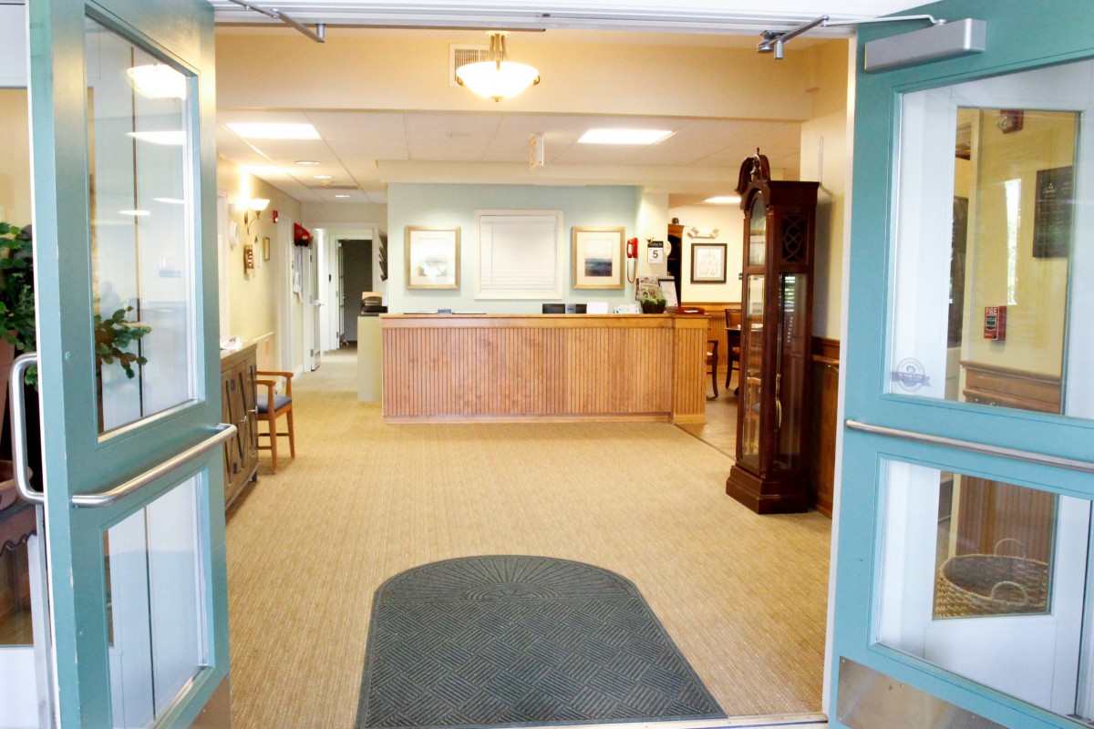 A reception area with a wooden desk and furnishings, leading into a hallway.