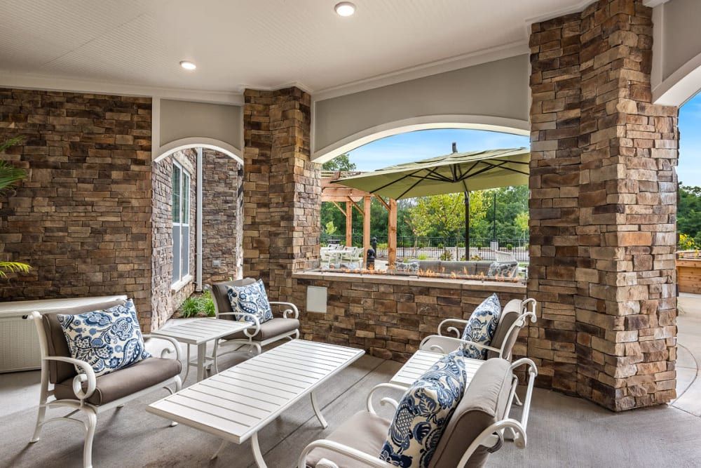 A cozy outdoor patio area with stone walls and comfortable seating overlooking a lush landscape.