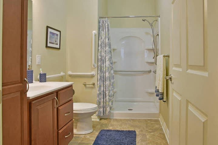 A modern bathroom with a shower, toilet, sink, and towel rack.