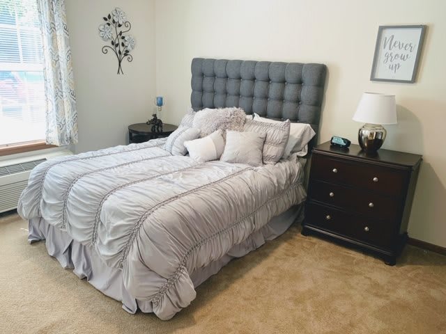 A neatly arranged bedroom with a stylish gray headboard and matching bedding.