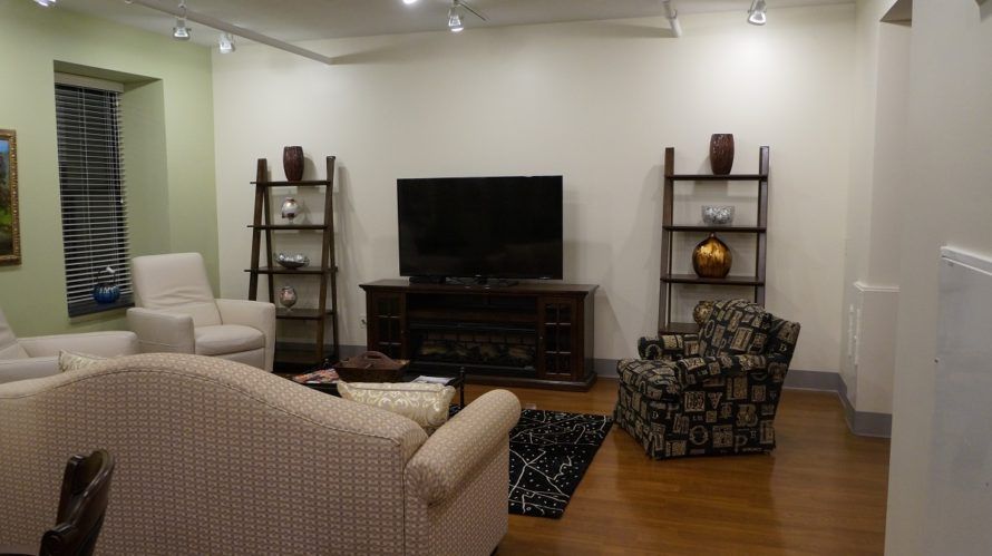 A modern living room with comfortable seating, featuring a large TV and decorative shelving units.