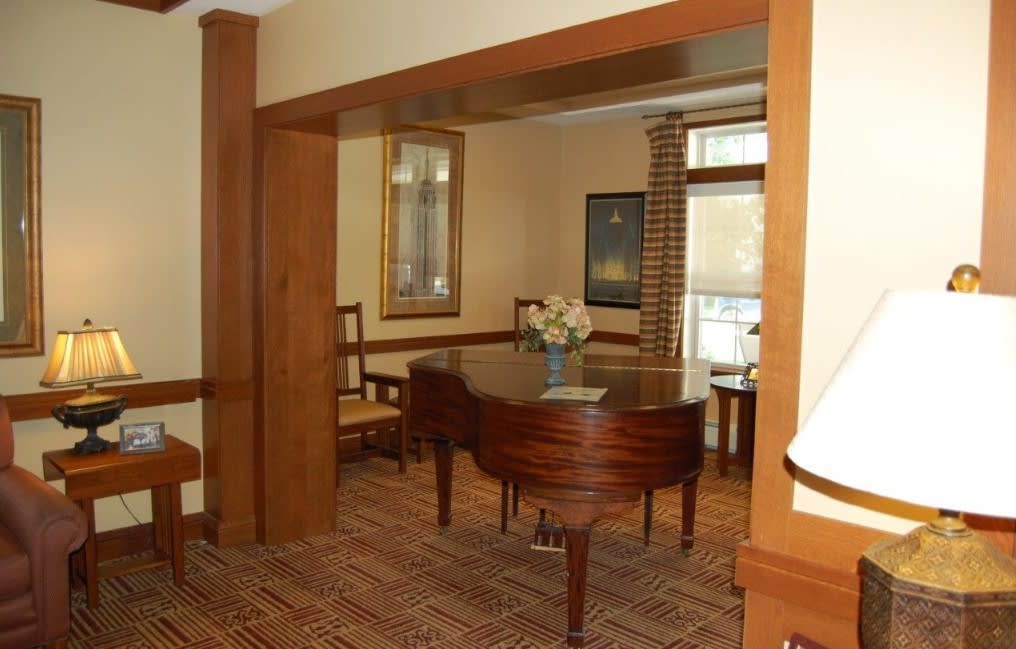 A cozy room featuring a grand piano with wooden decor.