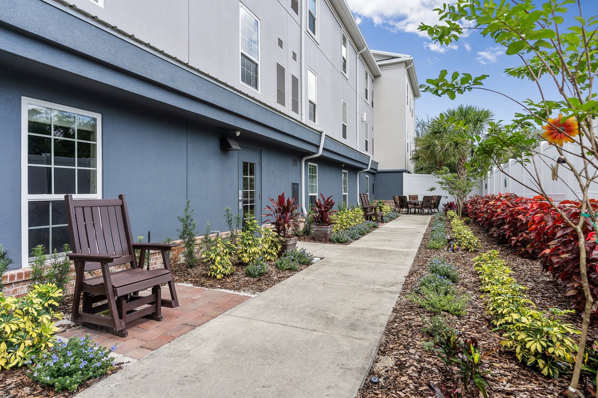 A well-maintained sidewalk lined with plants and outdoor seating in a residential area.