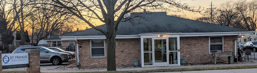 A cozy brick house with a large tree in the front yard during sunset.