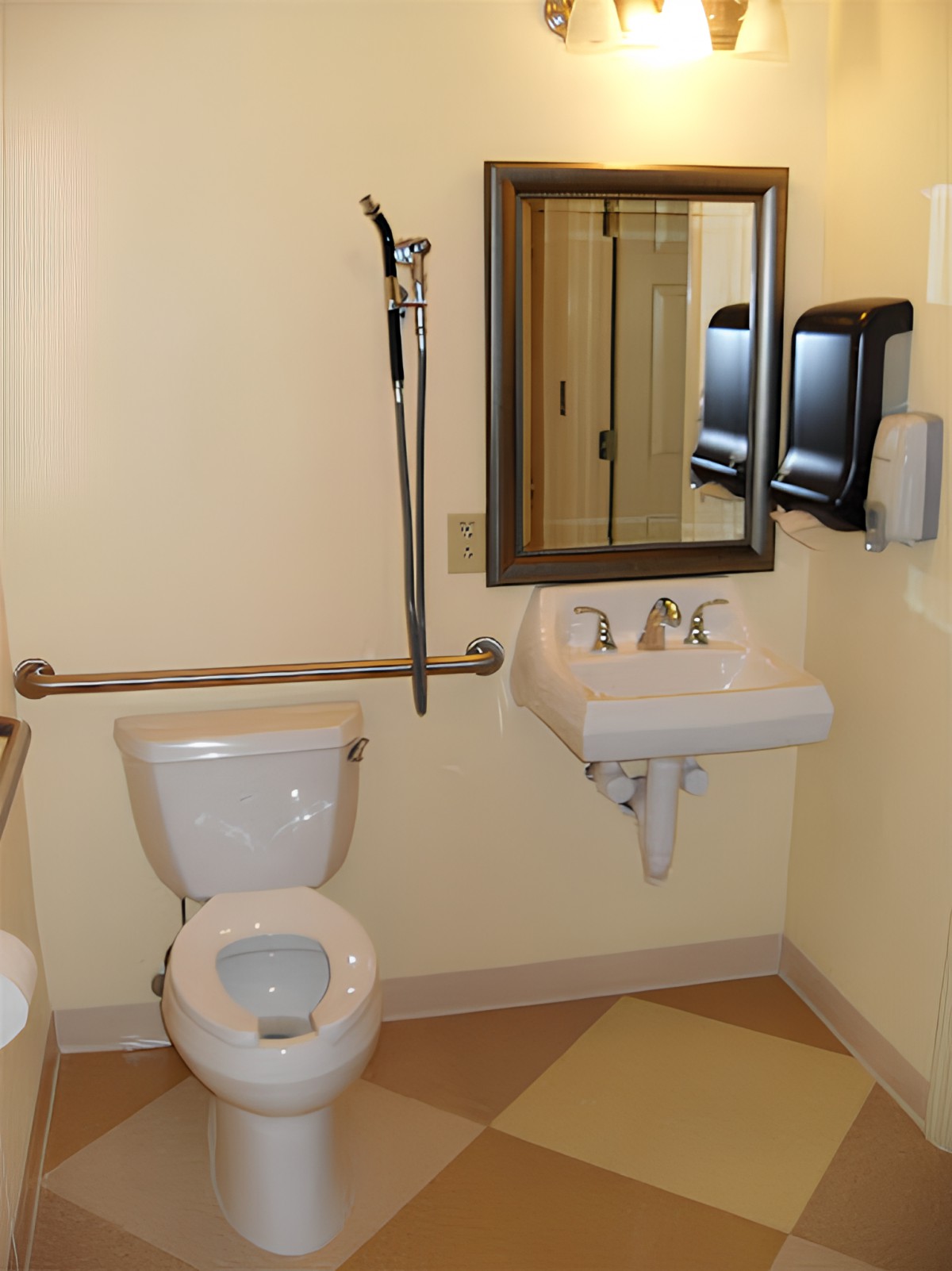 An accessible bathroom with a toilet, sink, and handrails.