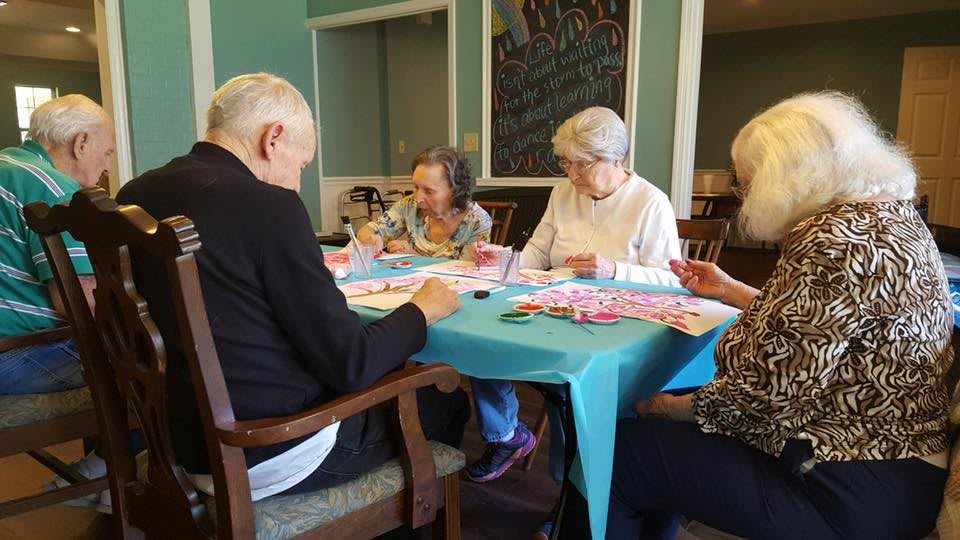 A group of seniors participating in an art activity indoors.
