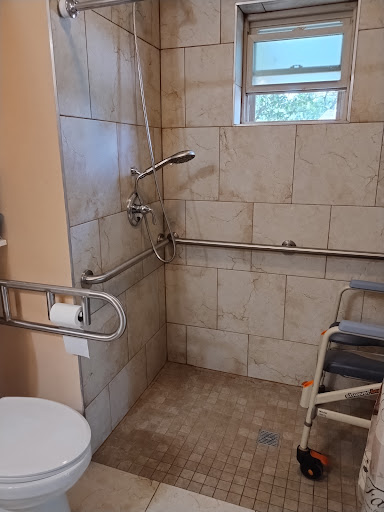 A well-equipped accessible bathroom with safety features such as handrails and a shower chair.
