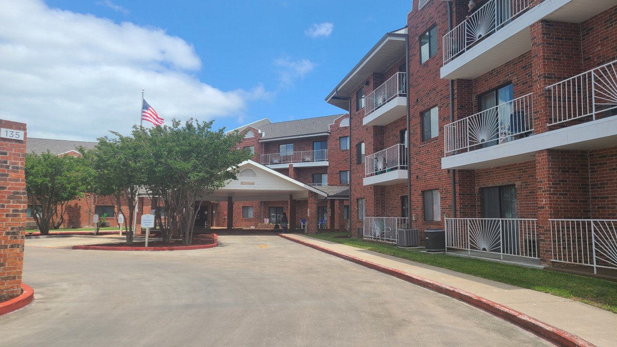 A view of a brick apartment building with balconies and an entrance drive.