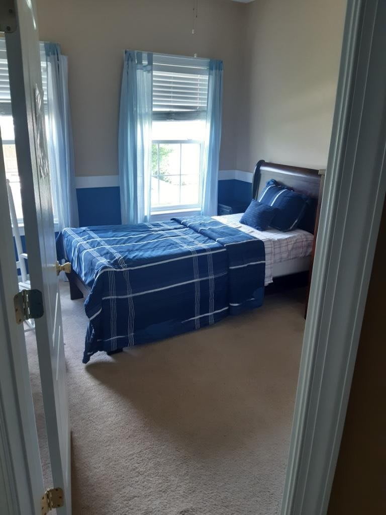 A cozy bedroom with a single bed and blue plaid bedding.