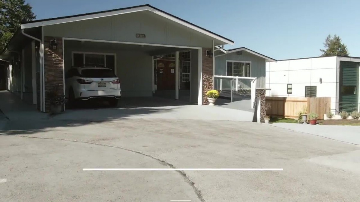 A suburban house with a carport and driveway on a sunny day.
