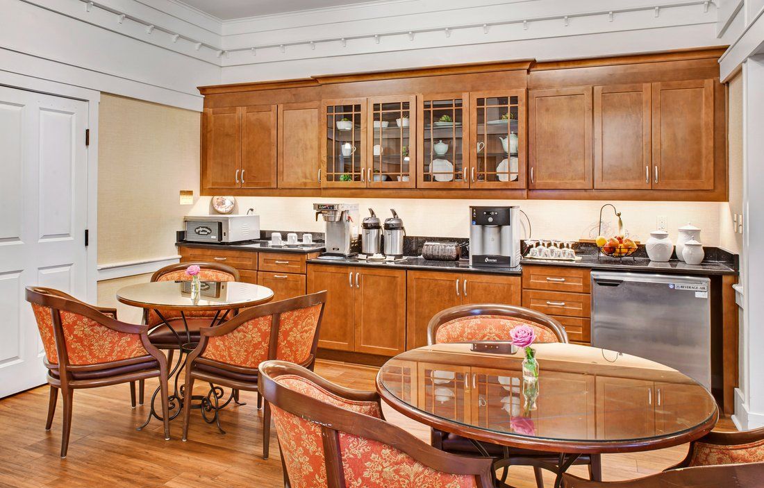 A cozy dining area with wooden cabinets and tables, featuring a coffee station.