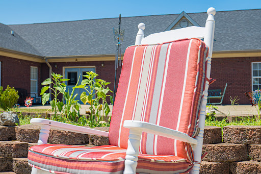 A cozy rocking chair with striped cushions, inviting relaxation in a sunlit garden.