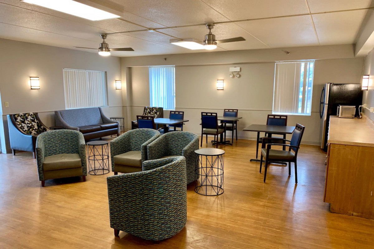 A comfortable lounge area with chairs and tables arranged on a wooden floor.