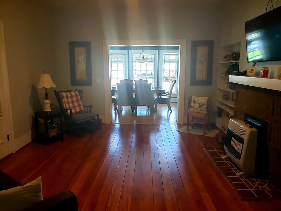 A cozy living room leading into a dining area with hardwood floors and stylish furniture.
