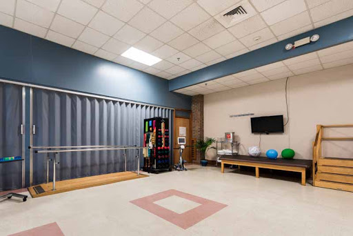A spacious rehabilitation room equipped with therapy tools, exercise equipment, and a vending machine.
