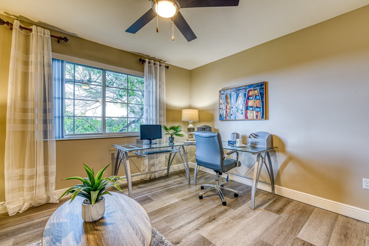 A cozy home office with modern decor, featuring a glass desk, ergonomic chair, and natural lighting.