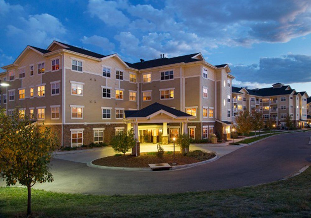 A well-lit residential building at night with landscaped surroundings.