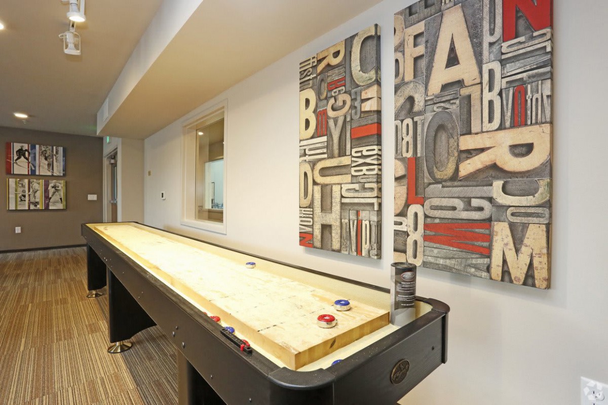An indoor game room featuring a shuffleboard table and decorative wall art.