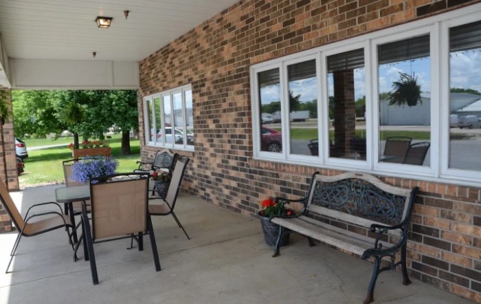 A cozy outdoor patio with seating and a brick wall.