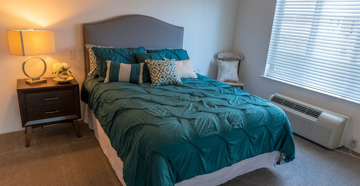 A cozy bedroom with a teal comforter and decorative pillows.