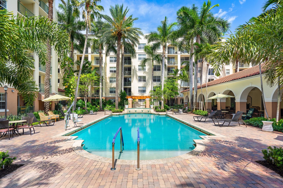 A luxurious hotel with a large swimming pool surrounded by palm trees, perfect for a relaxing vacation.