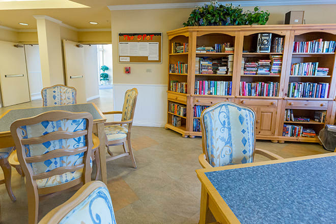 A cozy reading room with bookshelves, tables, and chairs.