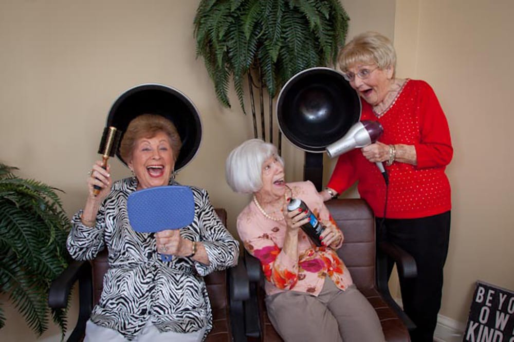Three elderly women enjoying a fun time at the hair salon, laughing together.