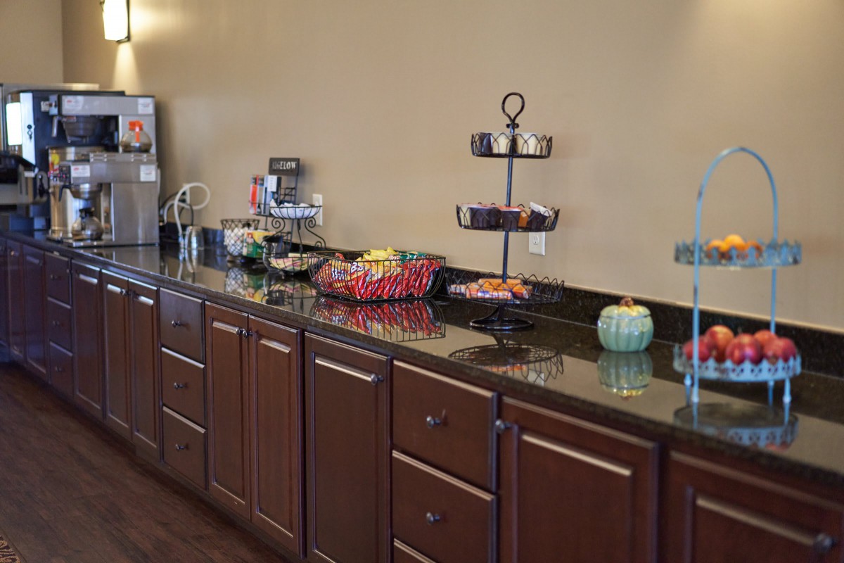 A breakfast area with a variety of snacks and a coffee station on a countertop.