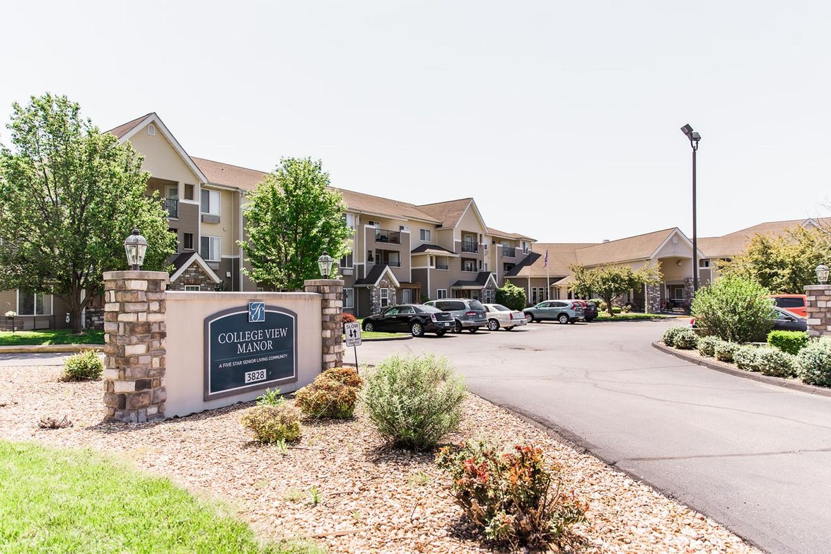 A residential apartment complex with a parking lot and landscaping.