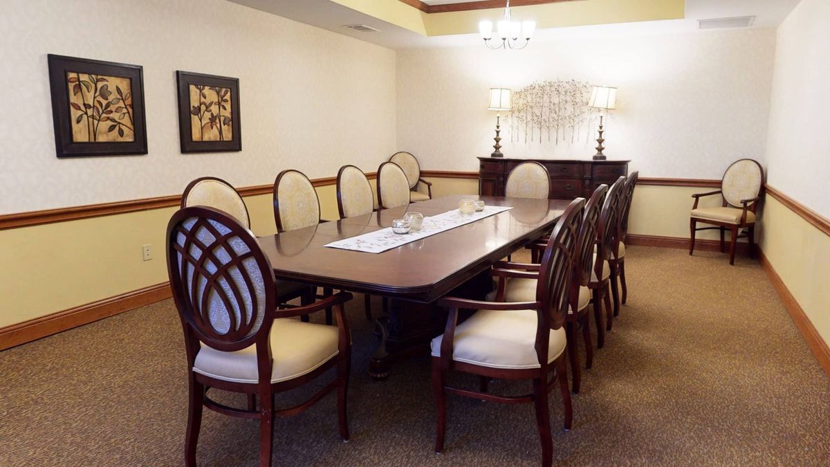 A neatly arranged conference room with a long table and upholstered chairs.