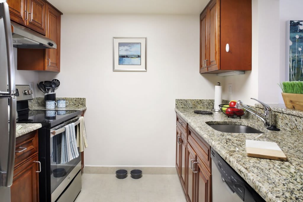 A modern kitchen with wooden cabinets, granite countertops, and stainless steel appliances.