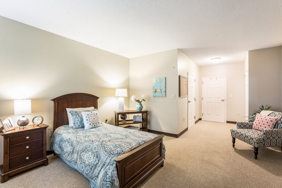 A cozy bedroom with a wooden bed frame, decorative pillows, and a side table with a lamp.