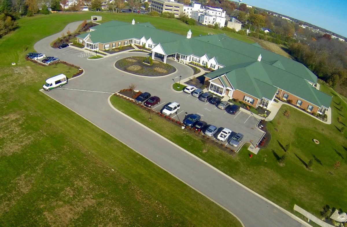 Aerial view of a building complex with a green roof and parking lot.