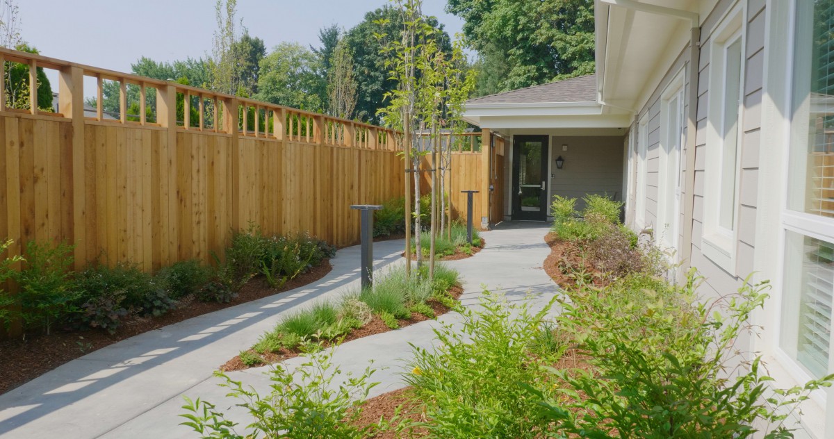 A neatly landscaped garden with a winding pathway and wooden fencing.