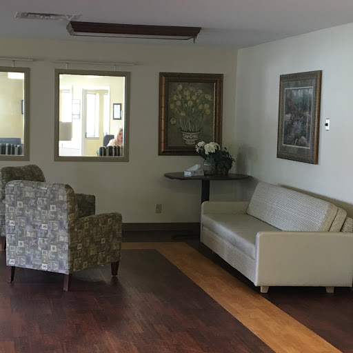 A cozy seating area in a reception space, featuring a sofa and armchairs alongside decorative artwork.