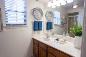 A neatly arranged bathroom with decorative elements and blue towels.
