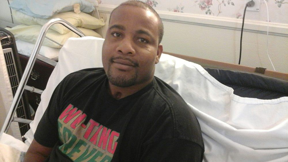 A man sitting in a hospital bed, looking at the camera with a relaxed expression.