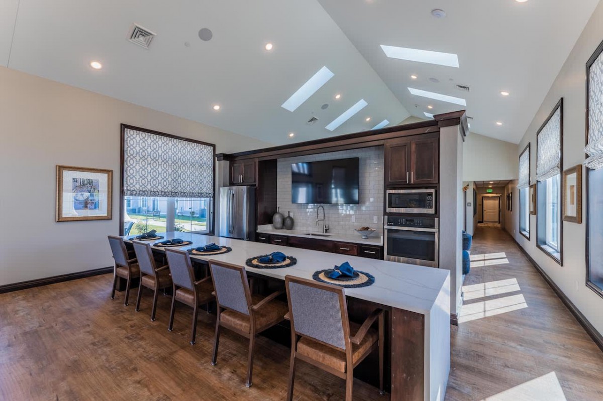A modern kitchen interior featuring a spacious island with barstools, sleek appliances, and abundant natural lighting.